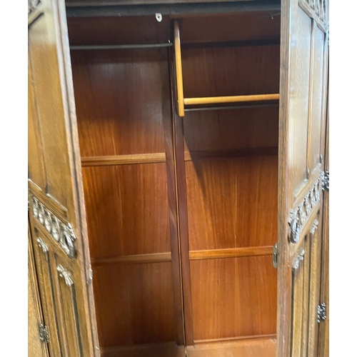 1660 - A vintage 20th century Jacobean Revival oak bedroom wardrobe having a flared top over two tall twin ... 