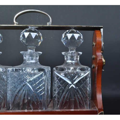 1766 - A vintage 20th century mahogany and brass bound three decanter tantalus. The tantalus with brass car... 