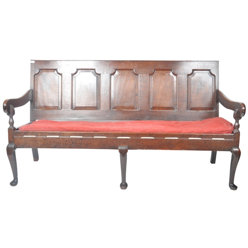 86 - A 19th Century carved oak settle bench having a fielded panel back with large armrests and red velou... 