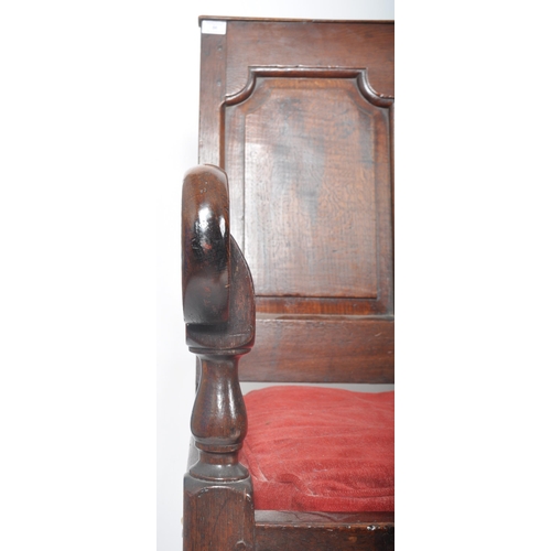 86 - A 19th Century carved oak settle bench having a fielded panel back with large armrests and red velou... 