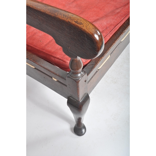 86 - A 19th Century carved oak settle bench having a fielded panel back with large armrests and red velou... 