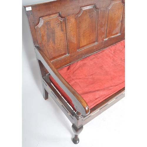 86 - A 19th Century carved oak settle bench having a fielded panel back with large armrests and red velou... 