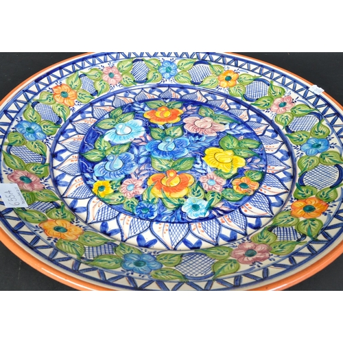 655a - A 20th Century continental floral decorated pottery charger plate. Having a repeating geometric patt... 