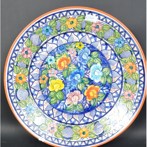 655a - A 20th Century continental floral decorated pottery charger plate. Having a repeating geometric patt... 