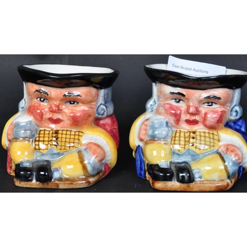 776 - A pair of 20th century Clarice Cliff pottery miniature toby jugs with blue & red gilets holding stei... 