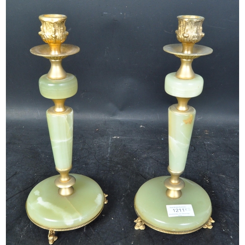 1211 - A pair of vintage mid 20th century onyx and gilt metal candlesticks. Each having polished agate shaf... 