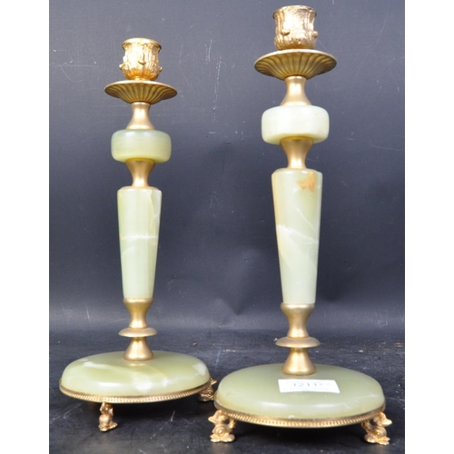 1211 - A pair of vintage mid 20th century onyx and gilt metal candlesticks. Each having polished agate shaf... 