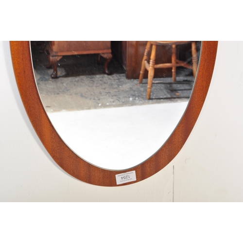 1254 - A retro vintage mid 20th Century teak wall hanging mirror. Of oval form with mirror mounted on a tea... 