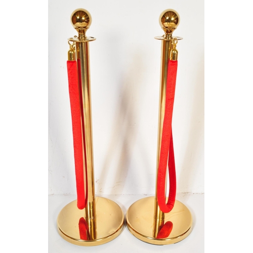 1286 - A pair of contemporary gilt metal pedestal rope barriers having single red rope across on circular p... 