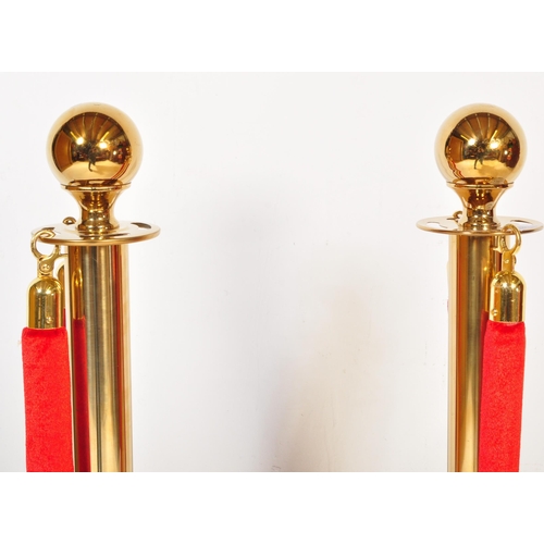 1286 - A pair of contemporary gilt metal pedestal rope barriers having single red rope across on circular p... 