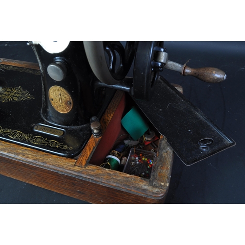 1476 - An early 20th century oak cased Singer ebonised & gilt sewing machine. Serial number Y8093800. The c... 