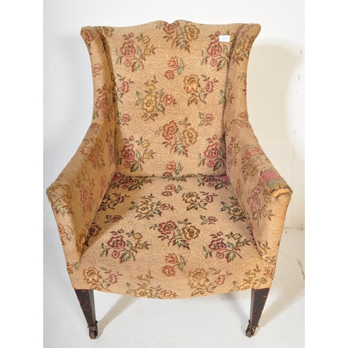 1493 - An Edwardian mahogany wingback armchair having crested swan neck to back rest over sloping elbow res... 