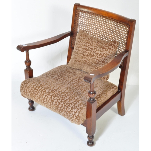 1606 - A vintage 20th Century low mahogany armchair. Having a rattan back straight arm rests, with foliate ... 