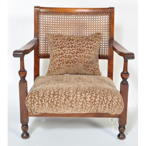 1606 - A vintage 20th Century low mahogany armchair. Having a rattan back straight arm rests, with foliate ... 