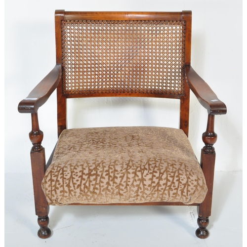 1606 - A vintage 20th Century low mahogany armchair. Having a rattan back straight arm rests, with foliate ... 