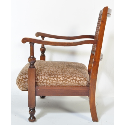 1606 - A vintage 20th Century low mahogany armchair. Having a rattan back straight arm rests, with foliate ... 