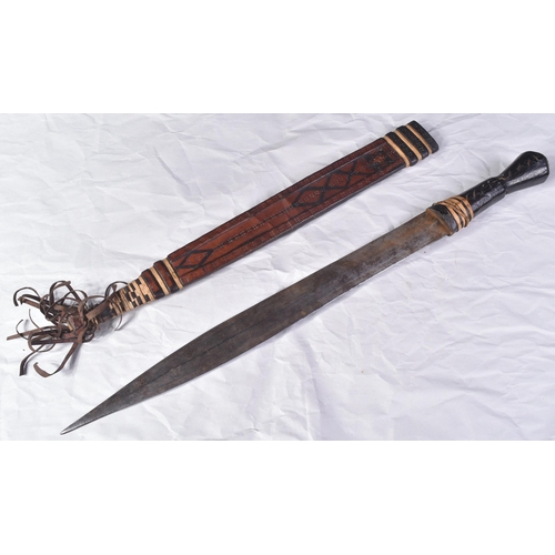 287 - An early 20th Century North African / Sudanese tribal sword. Leather grip over a wooden core and a f... 