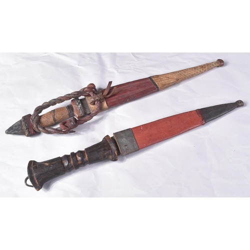 298 - Two North African tribal knives / daggers. Both with tapering blades housed in tooled leather scabba... 