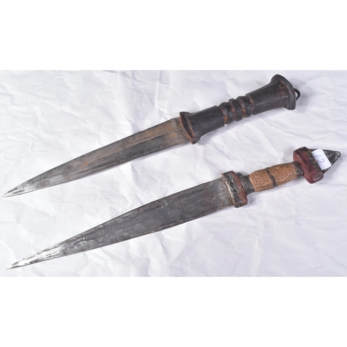 298 - Two North African tribal knives / daggers. Both with tapering blades housed in tooled leather scabba... 