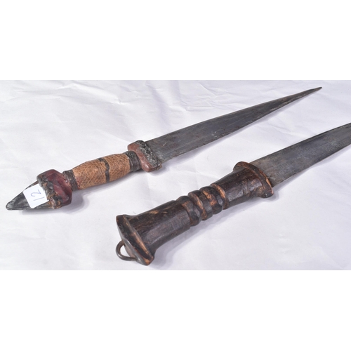 298 - Two North African tribal knives / daggers. Both with tapering blades housed in tooled leather scabba... 