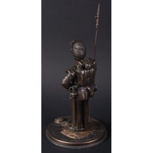 319 - A mid 20th Century bronzed figurine depicting a Royal Welsh Fusiliers Infantry soldier. The soldier ... 