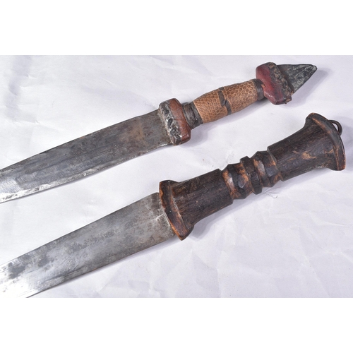 298 - Two North African tribal knives / daggers. Both with tapering blades housed in tooled leather scabba... 