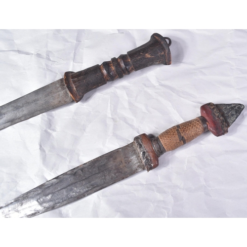 298 - Two North African tribal knives / daggers. Both with tapering blades housed in tooled leather scabba... 