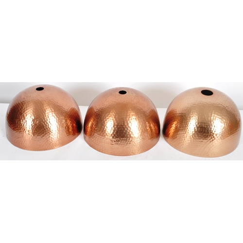 177 - A matching set of three Contemporary copper toned hand beaten ceiling light shades of domed form. Ea... 