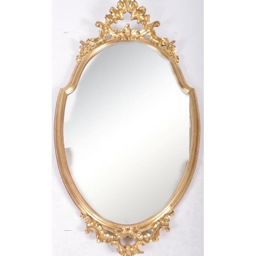 204 - A late 20th Century Hollywood Regency gilt frame pier mirror / hallway mirror having a shaped mirror... 