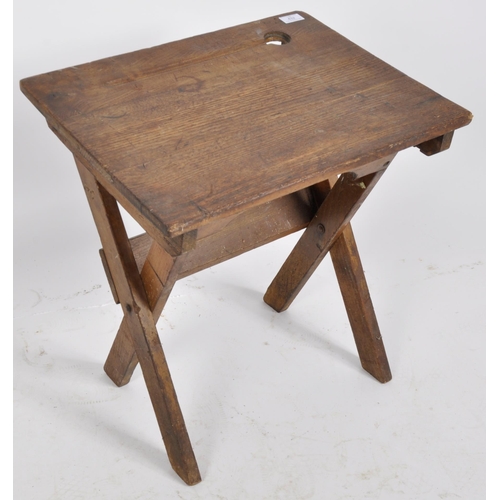 432 - An early 20th Century English school oak folding desk having a indent and inkwell holder to the top ... 