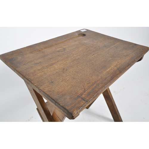 432 - An early 20th Century English school oak folding desk having a indent and inkwell holder to the top ... 