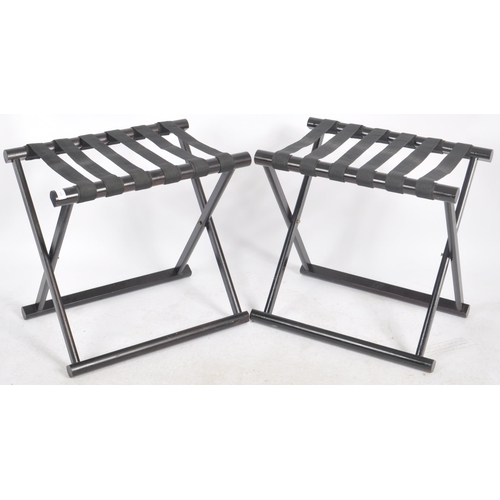 546 - A matching pair of Contemporary ebonised luggage rack stands with webbed tops and folding X-frame st... 