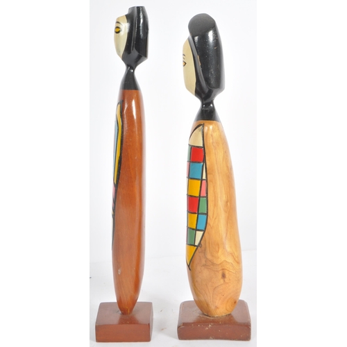 57 - Frank Coronado - A pair of mid Century carved teak stylized figures each with two tone faces and abs... 