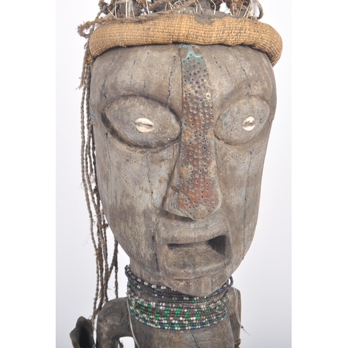 593 - A large 20th Century tribal African figure with horn set to head with inset shells to eyes. Glass be... 