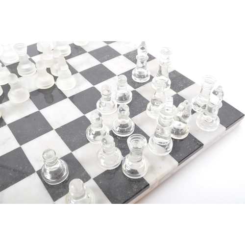 258 - A vintage 20th century marble & slate chess board together with matching glass chess pieces. The boa... 