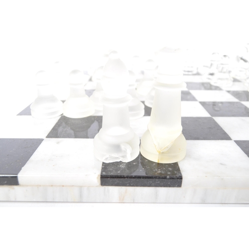 258 - A vintage 20th century marble & slate chess board together with matching glass chess pieces. The boa... 