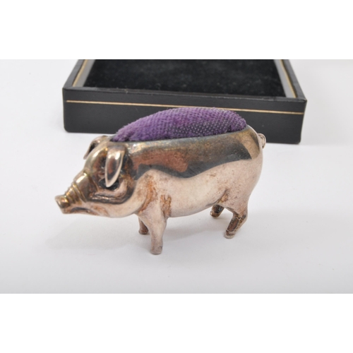 306 - An early 20th century white metal pin cushion in the form of a pig with blue cushion to back. Measur... 