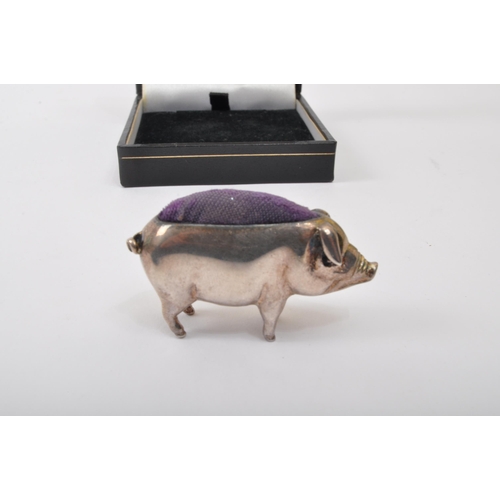 306 - An early 20th century white metal pin cushion in the form of a pig with blue cushion to back. Measur... 