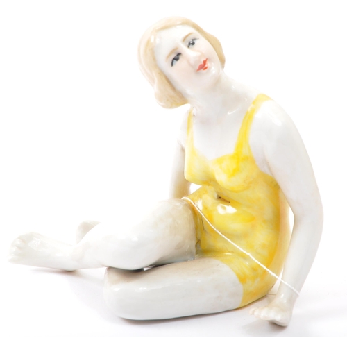 101a - Two 20th Century ceramic Art Deco style figurines. The lot to include a seated figure of a lady in a... 