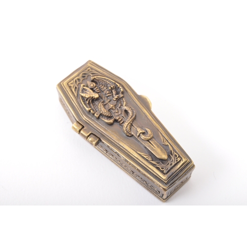 261a - A brass vesta case in the form of a coffin. The coffin having moulded dragon and sword to the lid re... 