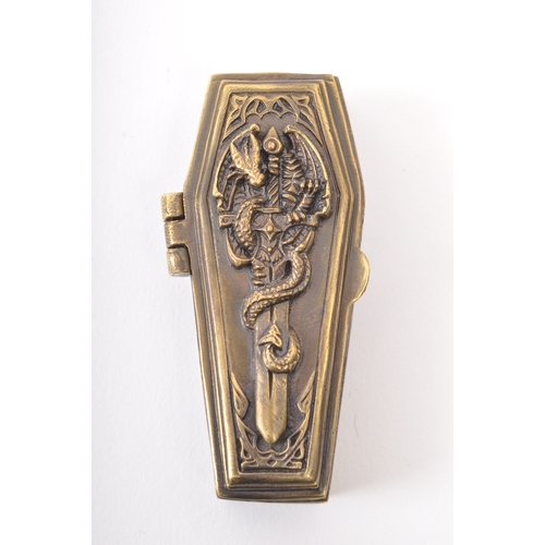 261a - A brass vesta case in the form of a coffin. The coffin having moulded dragon and sword to the lid re... 