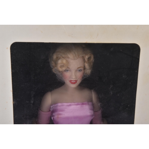 323 - A Franklin Mint made Marilyn Monroe portrait doll. The porcelain doll with pink satin dress, hand pa... 