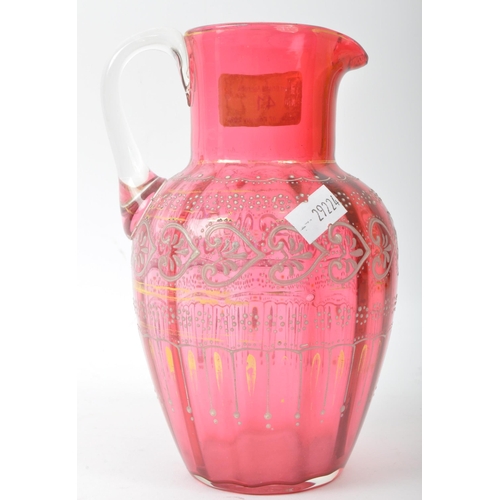 41 - A 19th Century Bohemian cranberry glass jug decanter. Having a spouted rim, gilt and enamel decorate... 