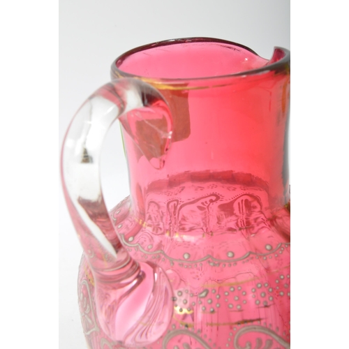 41 - A 19th Century Bohemian cranberry glass jug decanter. Having a spouted rim, gilt and enamel decorate... 