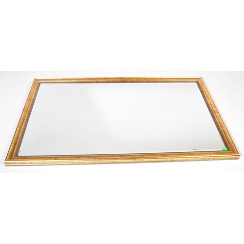 1048 - A large early 20th Century gilt over mantel mirror. Of rectangular form with gilt wood with bevelled... 