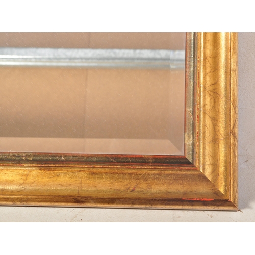 1048 - A large early 20th Century gilt over mantel mirror. Of rectangular form with gilt wood with bevelled... 