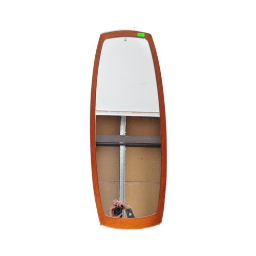 637 - A retro vintage mid 20th Century teak framed wall hanging mirror of curved rectangular form. It meas... 