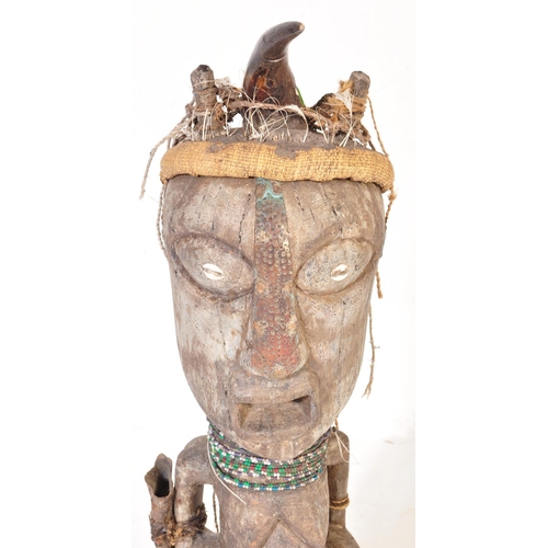 707 - A large 20th Century tribal African figure with horn set to head with inset shells to eyes. Glass be... 