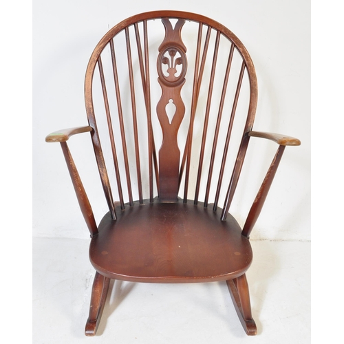 750 - A retro vintage mid 20th Century dark beech and elm rocking chair. With rounded spindle wheelback wi... 