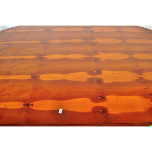 802 - A vintage 20th Century yew wood dining table with chairs. The table of oval form with veneer top ree... 